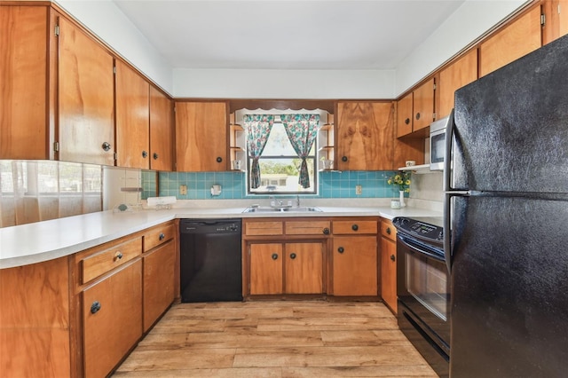 kitchen with tasteful backsplash, sink, light wood-type flooring, and black appliances