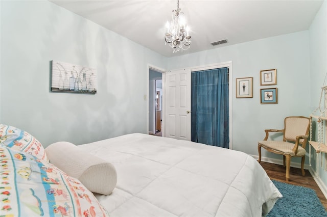 bedroom featuring hardwood / wood-style floors, a notable chandelier, and a closet