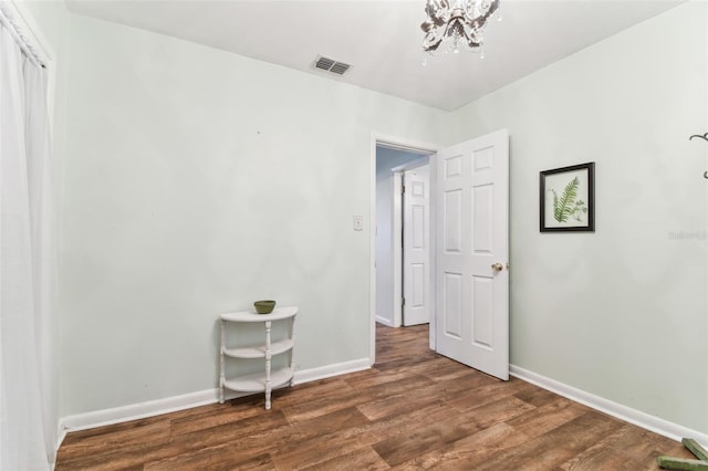 spare room featuring dark hardwood / wood-style flooring and a notable chandelier