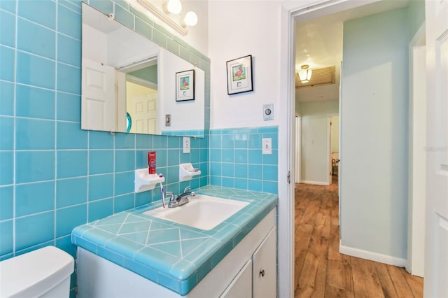 bathroom with tile walls, vanity, wood-type flooring, and toilet