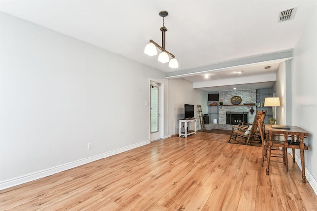 living room with a brick fireplace and light hardwood / wood-style flooring