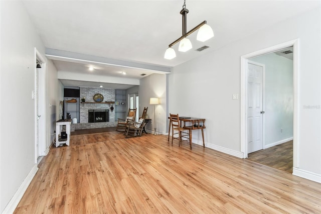 unfurnished living room with hardwood / wood-style floors, beam ceiling, and a fireplace