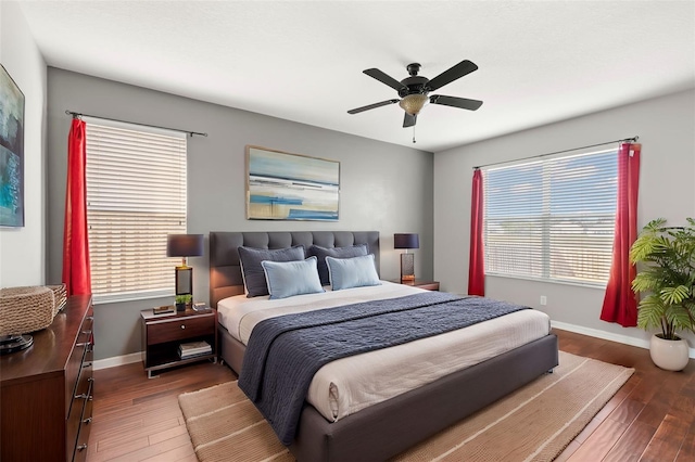 bedroom featuring multiple windows, dark hardwood / wood-style floors, and ceiling fan