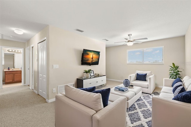 living room with sink, light colored carpet, and ceiling fan