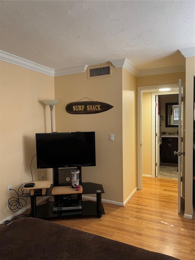 interior space with crown molding, a textured ceiling, and light wood-type flooring