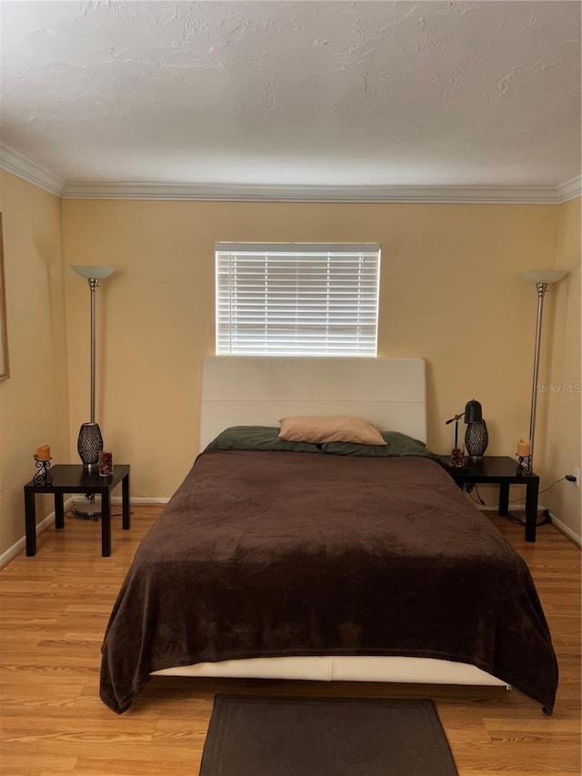 bedroom with crown molding, a textured ceiling, and light wood-type flooring