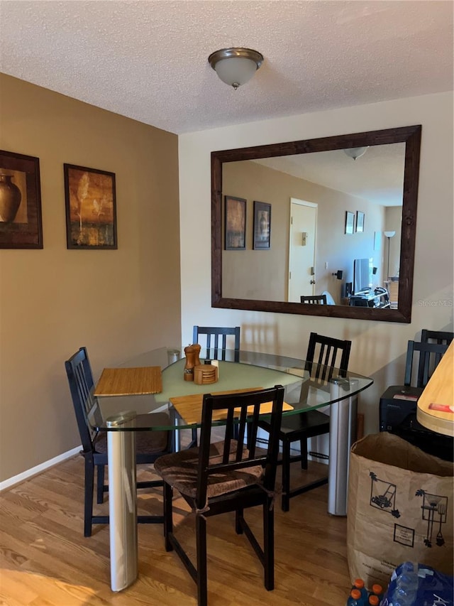 dining room featuring a textured ceiling and light hardwood / wood-style floors