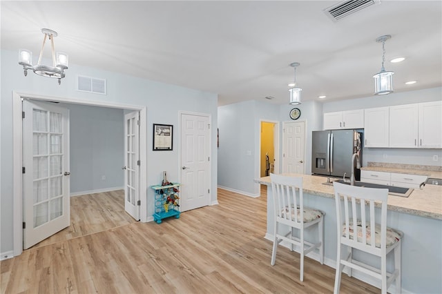 kitchen with white cabinetry, stainless steel fridge with ice dispenser, decorative light fixtures, and french doors