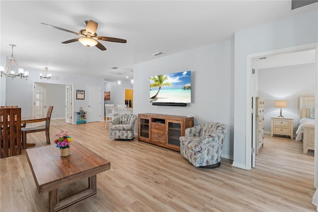 living room featuring ceiling fan with notable chandelier and light wood-type flooring