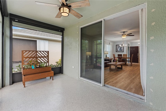 sunroom / solarium featuring ceiling fan with notable chandelier