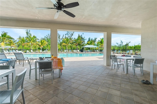 view of patio with a community pool and ceiling fan