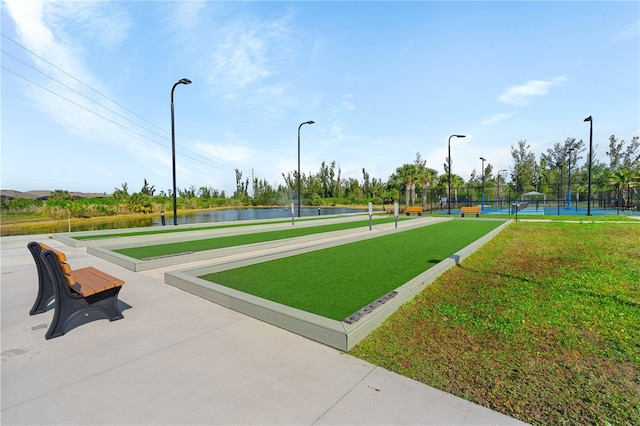 view of home's community with a water view and tennis court