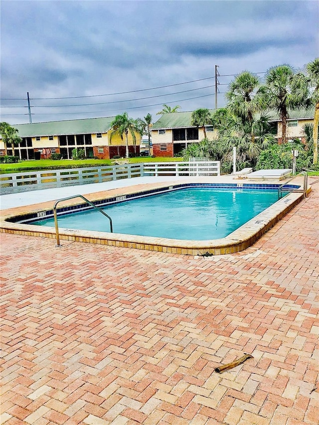 community pool with a patio and fence