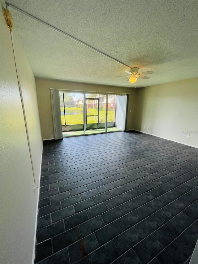 spare room featuring ceiling fan, baseboards, and a textured ceiling