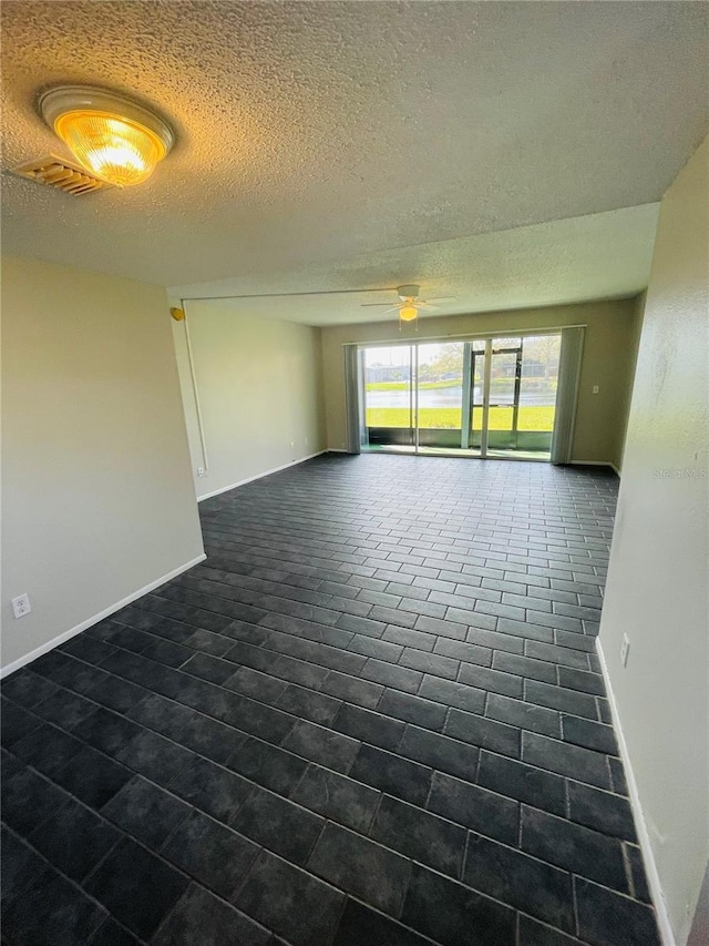 empty room featuring a ceiling fan, visible vents, baseboards, and a textured ceiling