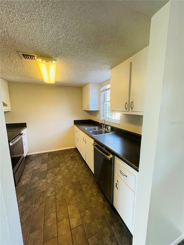 kitchen featuring stainless steel appliances, dark countertops, a sink, and white cabinetry