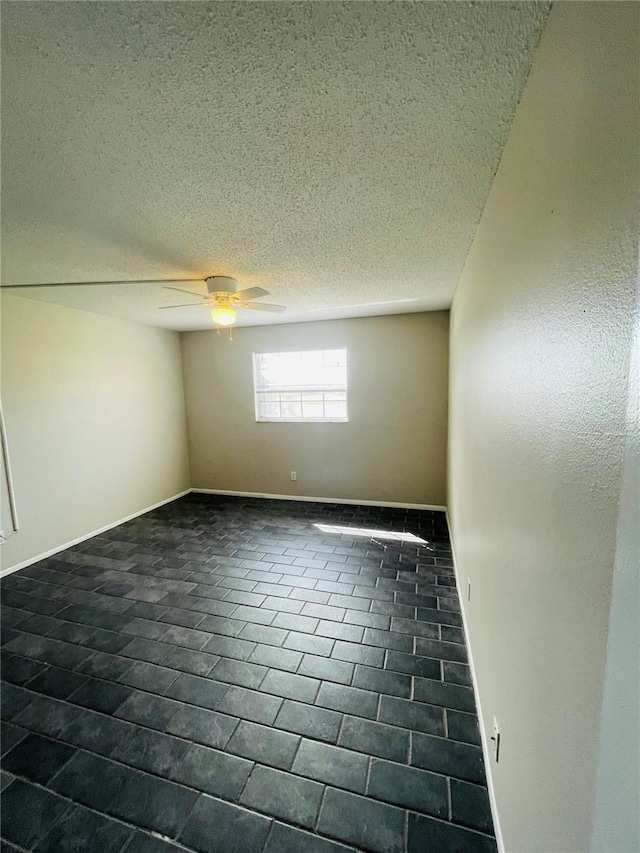 spare room with ceiling fan, a textured ceiling, and baseboards