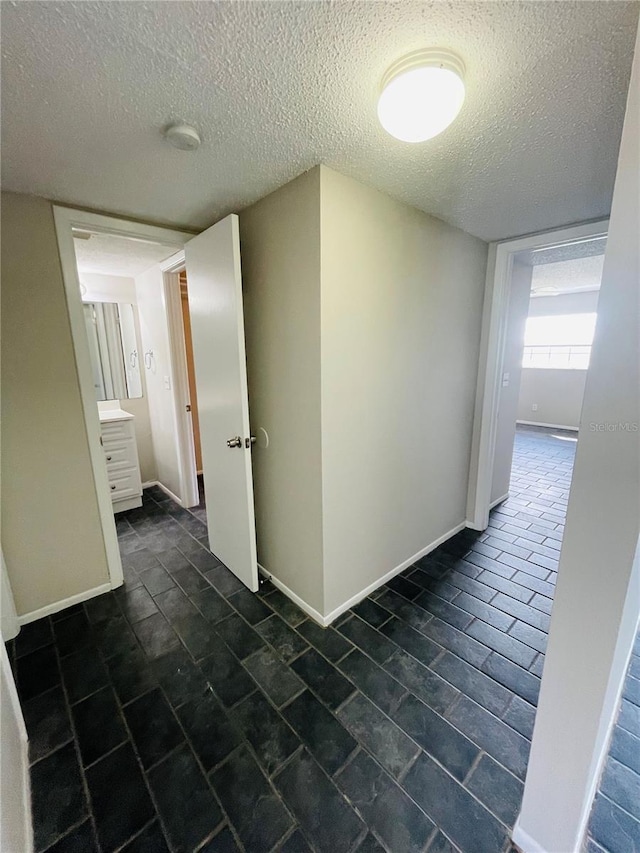 hall featuring baseboards and a textured ceiling