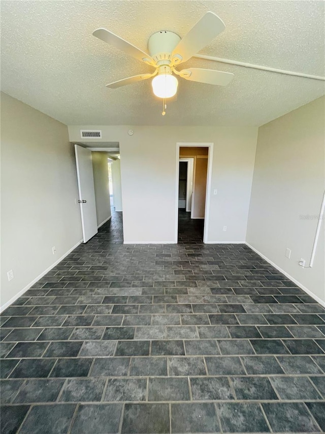 empty room featuring visible vents, ceiling fan, a textured ceiling, and baseboards