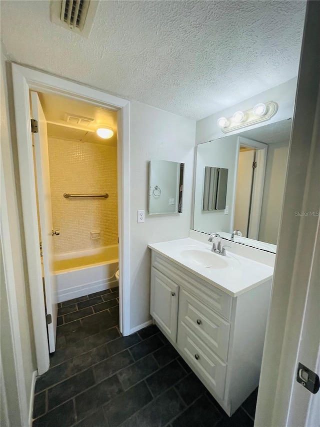 full bath with a textured ceiling, shower / bathtub combination, vanity, visible vents, and baseboards