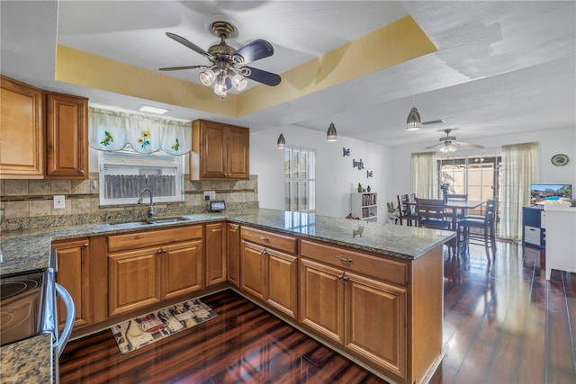 kitchen featuring a raised ceiling, electric stove, sink, and kitchen peninsula