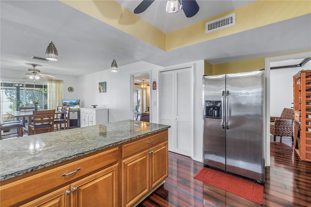 kitchen with stone countertops, dark hardwood / wood-style floors, decorative light fixtures, ceiling fan, and stainless steel refrigerator with ice dispenser