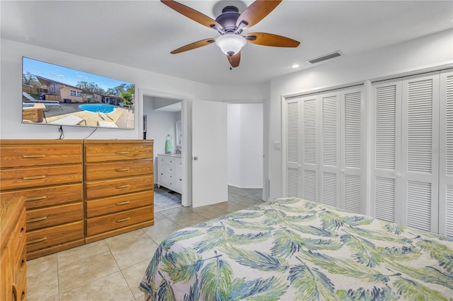 tiled bedroom featuring multiple closets, ceiling fan, and ensuite bathroom