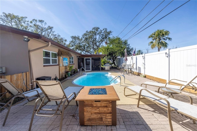 view of pool featuring a fire pit, a sunroom, and a patio