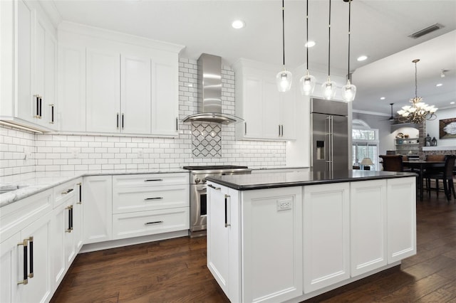 kitchen featuring white cabinetry, high end appliances, hanging light fixtures, and wall chimney exhaust hood