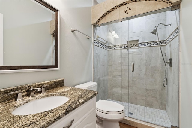 bathroom featuring vanity, a shower with door, and toilet