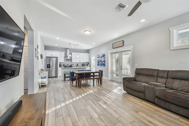 living room featuring ceiling fan, plenty of natural light, and light hardwood / wood-style floors