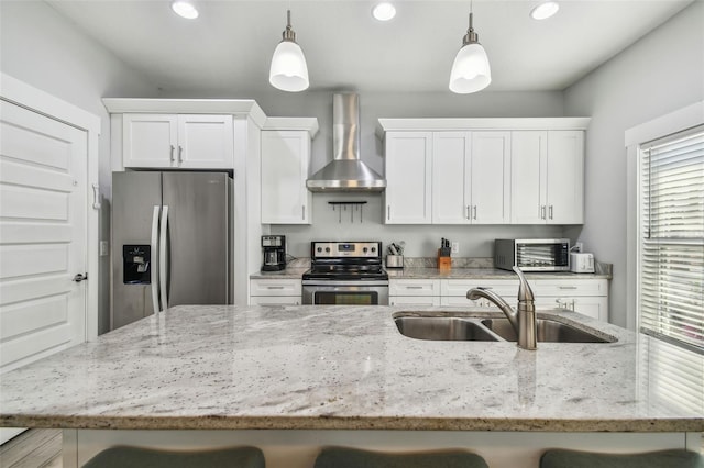 kitchen featuring decorative light fixtures, sink, white cabinets, stainless steel appliances, and wall chimney exhaust hood