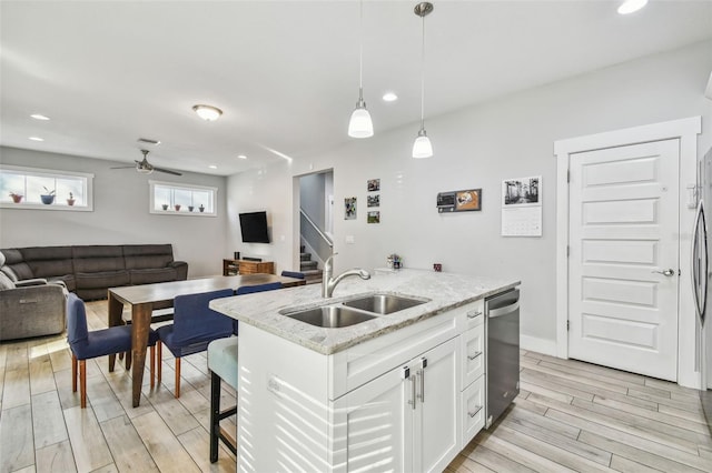 kitchen featuring pendant lighting, dishwasher, white cabinetry, sink, and a kitchen island with sink