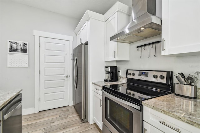 kitchen featuring white cabinetry, appliances with stainless steel finishes, wall chimney exhaust hood, and light stone counters