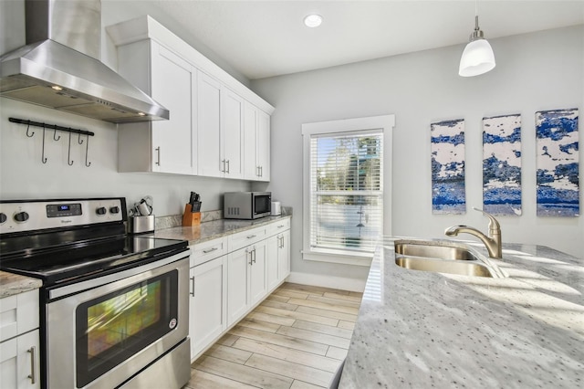 kitchen with ventilation hood, white cabinetry, sink, light stone counters, and stainless steel appliances