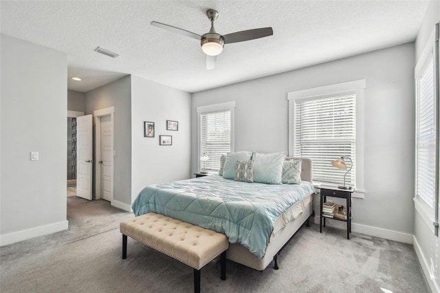 carpeted bedroom with multiple windows, ceiling fan, and a textured ceiling