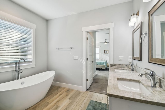 bathroom with wood-type flooring, vanity, ceiling fan, and a tub to relax in