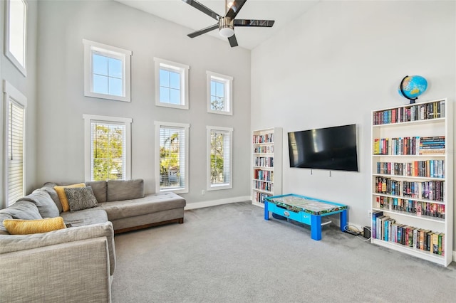 carpeted living room featuring a towering ceiling and ceiling fan