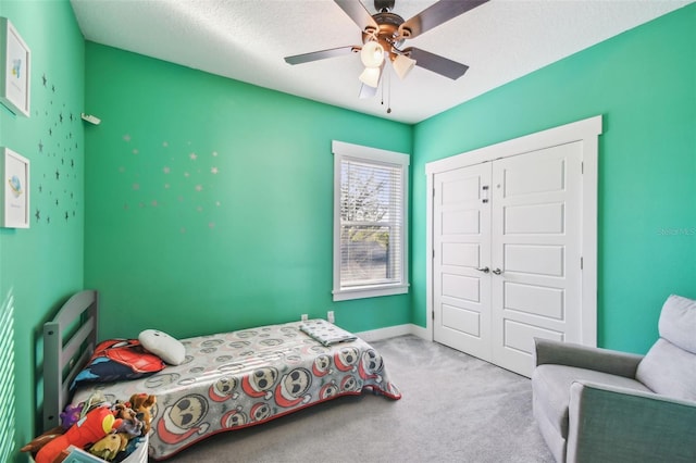 bedroom with ceiling fan, light colored carpet, a closet, and a textured ceiling