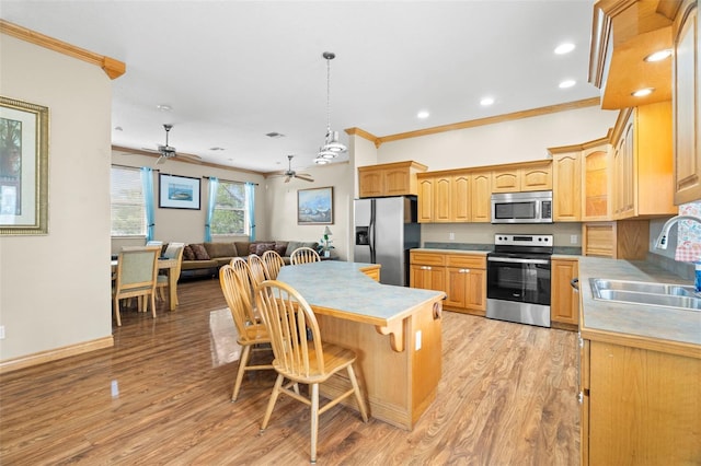 kitchen featuring decorative light fixtures, sink, a breakfast bar area, stainless steel appliances, and light wood-type flooring