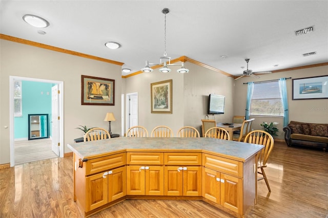 kitchen featuring light hardwood / wood-style flooring, a breakfast bar, ornamental molding, a kitchen island, and decorative light fixtures