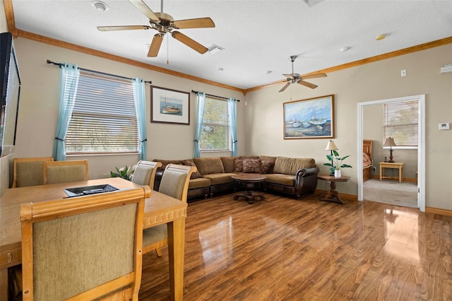 living room featuring wood-type flooring, ornamental molding, a textured ceiling, and ceiling fan