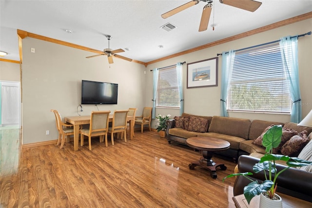 living room with crown molding, ceiling fan, plenty of natural light, and light hardwood / wood-style flooring