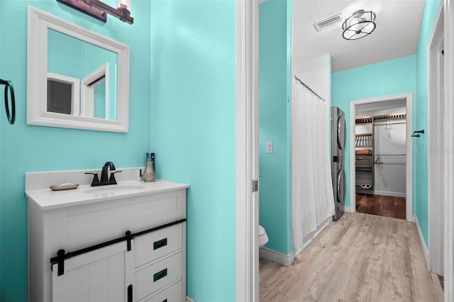 bathroom featuring toilet, a shower with curtain, a textured ceiling, vanity, and hardwood / wood-style floors