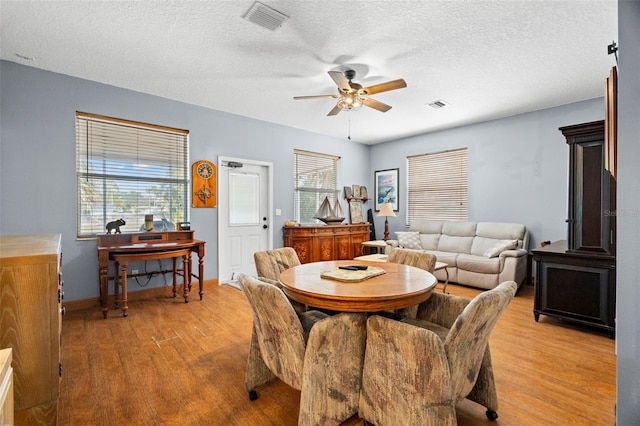 dining area with ceiling fan, plenty of natural light, a textured ceiling, and light hardwood / wood-style floors