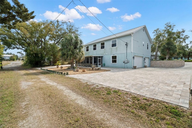 rear view of property featuring a garage and a sunroom