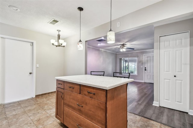 kitchen featuring pendant lighting, ceiling fan, ornamental molding, a textured ceiling, and a kitchen island