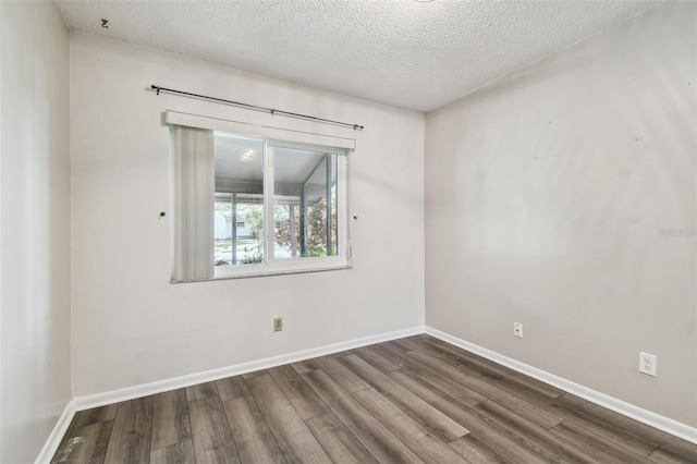 spare room with dark hardwood / wood-style floors and a textured ceiling