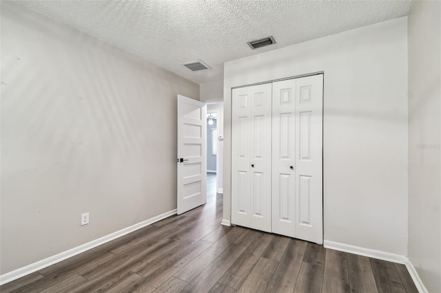 unfurnished bedroom with dark hardwood / wood-style flooring, a closet, and a textured ceiling