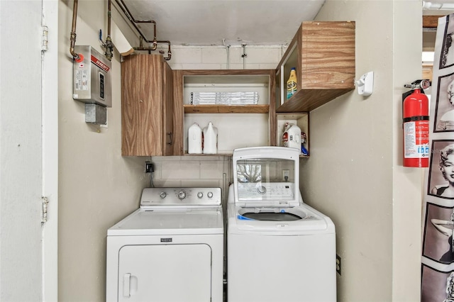 clothes washing area with cabinets and washing machine and clothes dryer